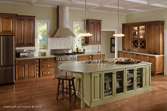 A wide view of a kitchen, with a light olive-green island counter, hardwood floor and wooden cabinetry.