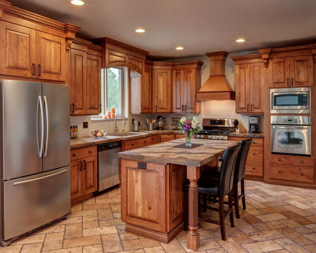 Picture of a kitchen with wooden cabinets and brown stone counters and floors, stainless steel appliances, and tan walls.