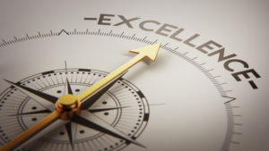 A compass with a golden needle points toward the word “Excellence” in the upper right of the compass circle.
